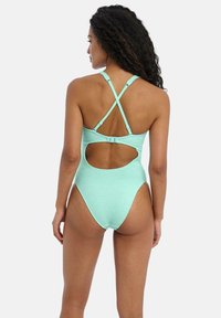 Un maillot de bain une pièce vert menthe avec un tissu texturé, des bretelles croisées, un dos découpé et un détail de fermeture sécurisé.