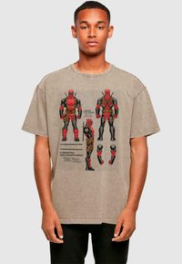 Gray oversized t-shirt with graphic print of a character in red and black, featuring detailed illustrations and text. Cotton material, casual design.