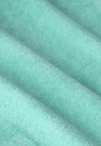 Zacht teal stof met een gestructureerd oppervlak, met subtiele kleurvariaties en een golvende vorm, die een luxe afwerking toont.