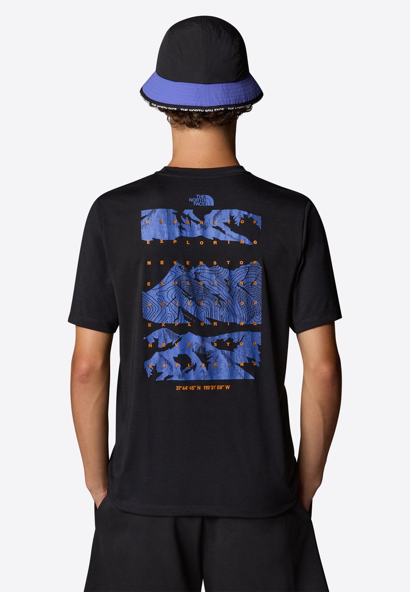 Camiseta negra de manga corta con un gráfico de montaña azul en la parte de atrás, acompañado de texto naranja y coordenadas. Complementada con un sombrero tipo cubo azul y negro.