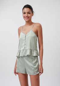 Ensemble de pyjama satin vert clair avec des bordures en dentelle. Comprend un haut peplum, des bretelles spaghetti réglables et un short assorti avec des accents en dentelle.