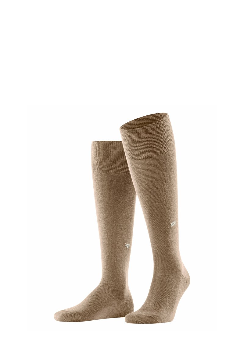 Calze color beige fino al ginocchio realizzate in un tessuto morbido. La parte superiore a coste ha una finitura liscia e presenta un piccolo emblemma decorativo vicino alla caviglia.