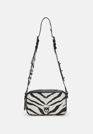Lille rektangulær crossbody taske med sort-hvide zebra striber og justerbar rem hængende mod en hvid baggrund.