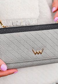 Gray textured handbag featuring a diamond pattern, black leather trim, and a gold logo accent. Chain strap visible on top.