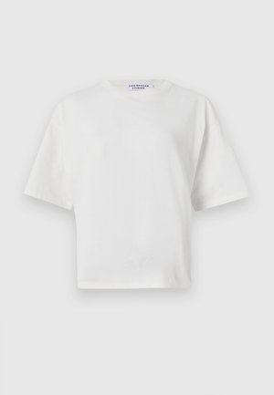 T-shirt blanc cropped avec un col rond, des manches courtes et une texture en coton lisse. Doté d'une étiquette de marque imprimée au niveau du col.