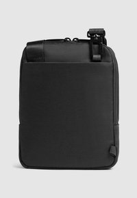 Zwarte, gestructureerde crossbodytas gemaakt van duurzaam materiaal. Voorzien van een ritssluiting aan de bovenzijde en een afneembare riem met een metalen sluiting.