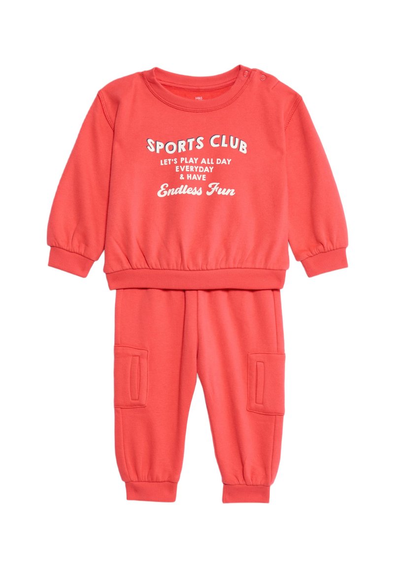 Korallenfarbendes Sportoutfit mit langen Ärmeln und Hose. Verfügt über gerippte Bündchen, elastischen Bund, Fronttaschen und weißen bedruckten Text.