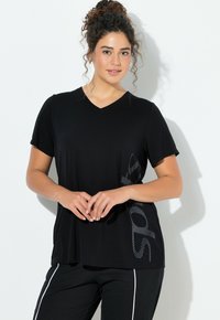 Camiseta negra con cuello en V en una tela suave, con mangas cortas y un patrón gráfico texturizado en el costado. Corte cuadrado con un ajuste relajado.