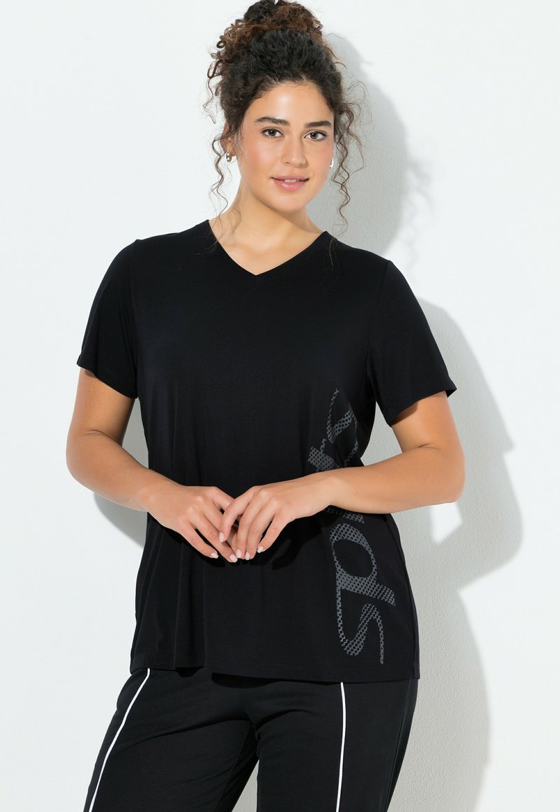 Camiseta negra con cuello en V en una tela suave, con mangas cortas y un patrón gráfico texturizado en el costado. Corte cuadrado con un ajuste relajado.