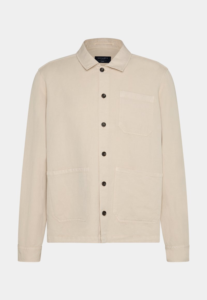 Beige Baumwolljacke mit Kragen, Knopfverschluss, zwei großen aufgesetzten Taschen und langen Ärmeln. Hervorhebung sind die dunklen Knöpfe und der lässige Schnitt.