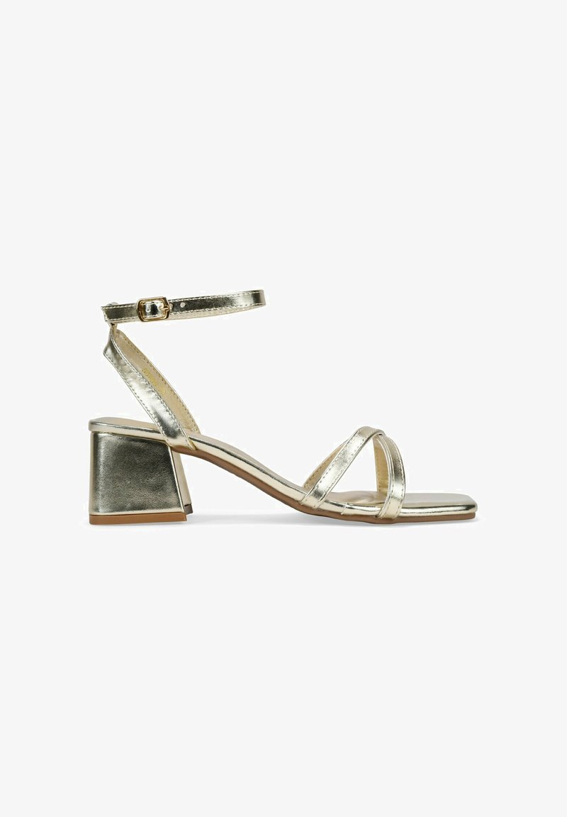 Metallic gold heeled sandals with a square block heel, slim ankle strap, and crisscrossed front bands. Smooth texture and minimal design.