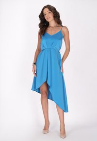 Rochie bleu din satin, fără mâneci, cu o poale asimetrică și decolteu în V. Are talie ajustată și atinge mijlocul coapsei pe o parte.