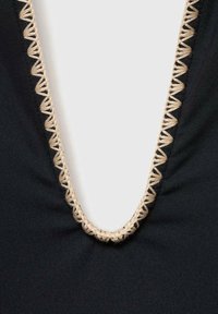 Schwarzes Kleidungsstück mit einem tiefen V-Ausschnitt, verziert mit einem kontrastierenden beigen Wellenrand entlang der Kante, aus weichem, dehnbarem Material.