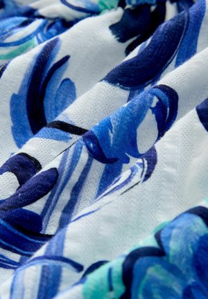 Modrobílá látka s květinovým a pruhovaným vzorem, zobrazující jemné záhyby a texturu v detailním záběru.