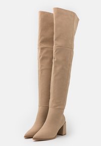 Béžové kozačky nad kolena z jemné semiše, s špičatou špičkou a masivním blokovým podpatkem, s hladkým, čistým designem.