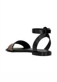 Black flat sandals featuring a woven front strap with tan accents, an ankle strap, and a smooth matte finish on the sole.