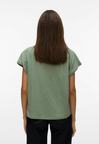 Žalias trumpas rankovės viršus, pagamintas iš minkštos medžiagos. Turi laisvą siluetą ir apvalų iškirpimą, tiesią apatinę dalį ir be matomų raštų.