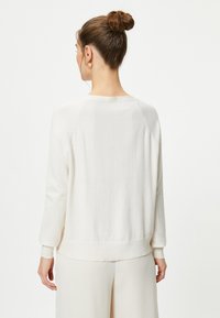 Jasnobeżowy sweter, miękka tekstura, okrągły dekolt, długie rękawy, ściągacze na rękawach i u dołu. Prosty, casualowy design z luźnym krojem.