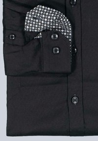 Schwarzes Hemd mit Knopfverschluss und umgeschlagenem Kragen, das das schwarz-weiße gemusterte Innenfutter zeigt, mit vier Knöpfen an den Manschetten und der Knopfleiste.