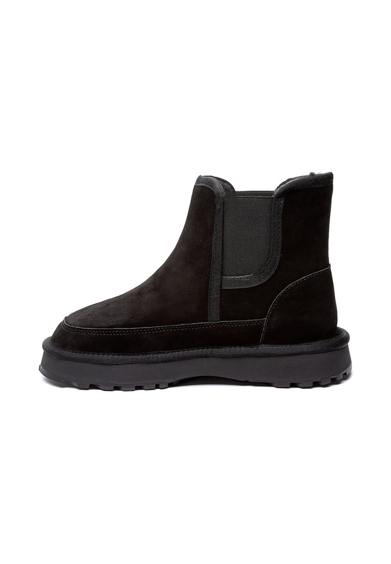 Čierne semišové členkové topánky s elastickými bočnými panelmi, zaoblenou špičkou a hrubou čiernou gumovou podrážkou s textúrovaným vzorom pre lepšiu priľnavosť.