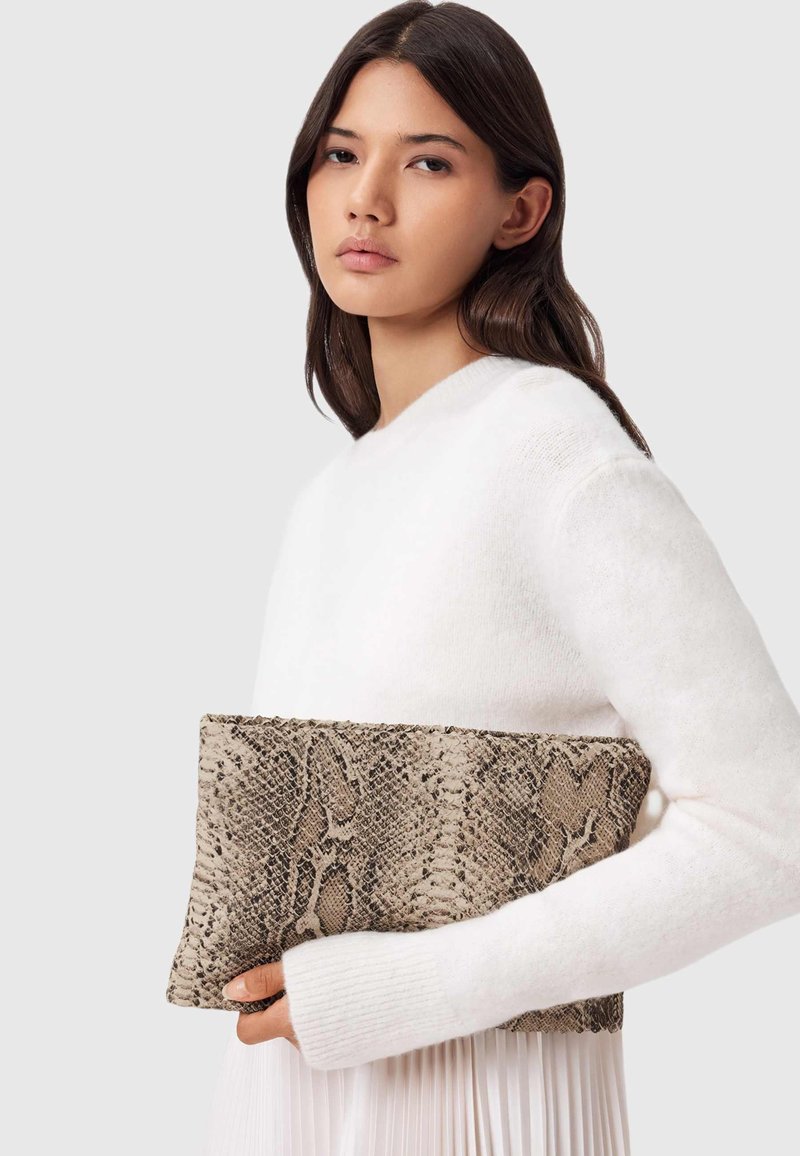 Schlangenledermuster-Clutch in Beige und Braun, rechteckige Form mit strukturiertem Oberfläche, gehalten gegen einen weißen Pullover.
