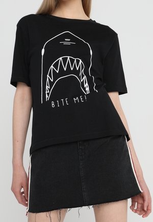 Czarny bawełniany t-shirt z białą grafiką rekina z otwartymi szczękami oraz napisem „BITE ME!” umieszczonym centralnie pod grafiką. Krótkie rękawy i luźny krój.