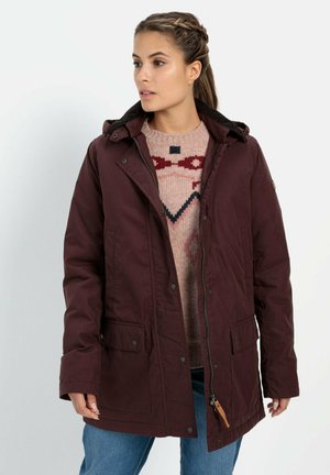 Bordeaux buitenjack met een rits en drukknoopsluiting, een capuchon en twee voorzakken. Getextureerde gebreide sweater in het roze met geometrische patronen eronder.