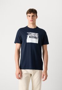 T-shirt in cotone blu navy con grafica rettangolare bianca recante la parola "BOSS" in grassetto nero, maniche corte, scollatura rotonda.