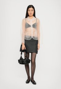 Käärme, pikad varrukad ja krae, hall rinnahoidja, tume teksaseelik, mustade mustritega sukkpüksid ja väike must kotike nurgakesega.