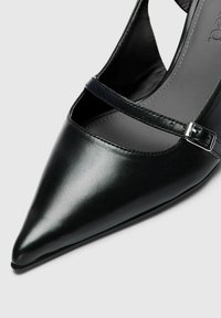 Melni ādas apavi ar norādītu purngalu, šauru potīti un metāla sprādzi. Gluda tekstūra un minimālistisks dizains ar atvērtu griezumu.