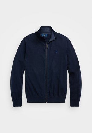 Námořnická zipová bunda vyrobená z jemné tkaniny. Má stojáčkový límec, ribbed manžety a malé vyšívané logo na levé hrudi.