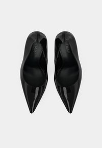 Black patent leather pointed-toe pumps with a smooth finish and open sides, featuring a sleek silhouette and minimalistic design.