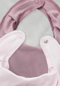 Due due bavaglini in tessuto: uno rosa chiaro e uno malva. Entrambi presentano chiusure a scatto e un materiale morbido e testurizzato con un bordo finito liscio.