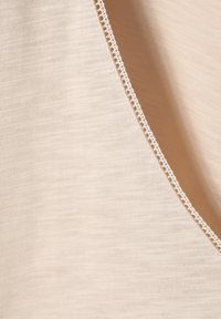 Beige fabric with a fine texture and subtle stripes, featuring a delicate lace trim along the curved edge.