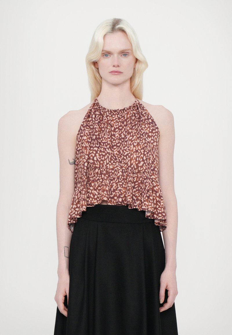 Haut halter en imprimé léopard marron avec encolure froncée et bas évasé, fabriqué en tissu léger. Porté avec une jupe noire.