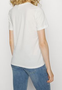 Hvid bomulds T-shirt med korte ærmer, rund halsudskæring og en afslappet pasform. Blød tekstur og klassisk design uden synlige mønstre eller detaljer.