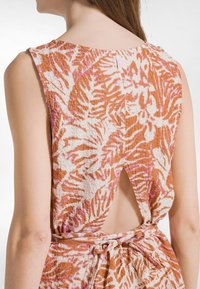 Jurk met een oranje-wit bladmotief, gestructureerd materiaal, mouwloos design en een uitsnijding aan de achterkant die vastgebonden is met een bijpassende riem.