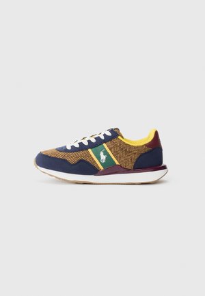 Marineblaue und braune Sneakers mit Fischgrätenmuster, gelben Akzenten, grüner Streifen, weißen Schnürsenkeln und Gummisohle. Logo an der Seite.