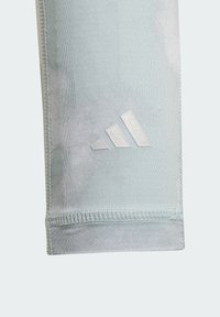 Light blue athletic pants made of smooth fabric, featuring a silver Adidas logo. Seam detailing visible at the bottom hem.
