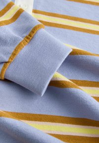 Tessuto a maglia azzurro chiaro con strisce orizzontali color senape, giallo e rosa pallido, e un dettagliato risvolto.