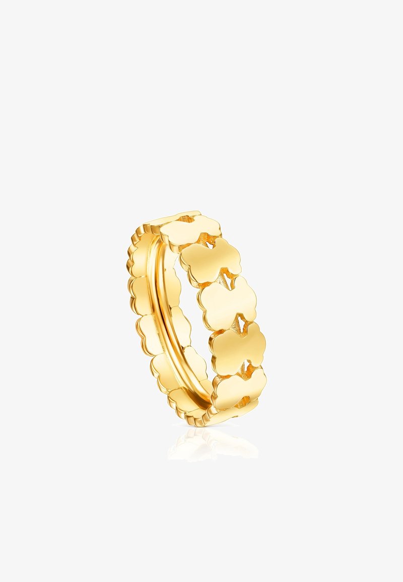 Anello in oro con un design a bordo ondulato e forme di trifoglio interconnesse, che presenta una finitura lucida e una texture liscia.