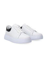 Weiße Ledersneaker mit schwarzem Absatz. Merkmale sind eine abgerundete Zehenpartie, flache Schnürsenkel und eine dicke weiße Sohle. Insgesamt glatte Oberfläche.