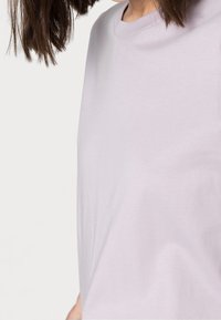 Lila t-shirt i mjuk bomull, med rund halsringning, korta ärmar och en slät yta utan synliga mönster eller dekorationer.