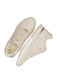 Beige tenisky s texturovaným svrškem, šněrováním a bílou podrážkou. Mají zlaté akcenty a výjimečný design na boku.