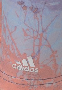 Haut sans manches Adidas avec un motif floral abstrait en rose clair et bleu, arborant un logo blanc et un tissu lisse et léger.