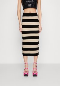 Stickad midikjol med alternerande svarta och beiga ränder. Matchad med rosa högklackade sandaler med ankelremmar.