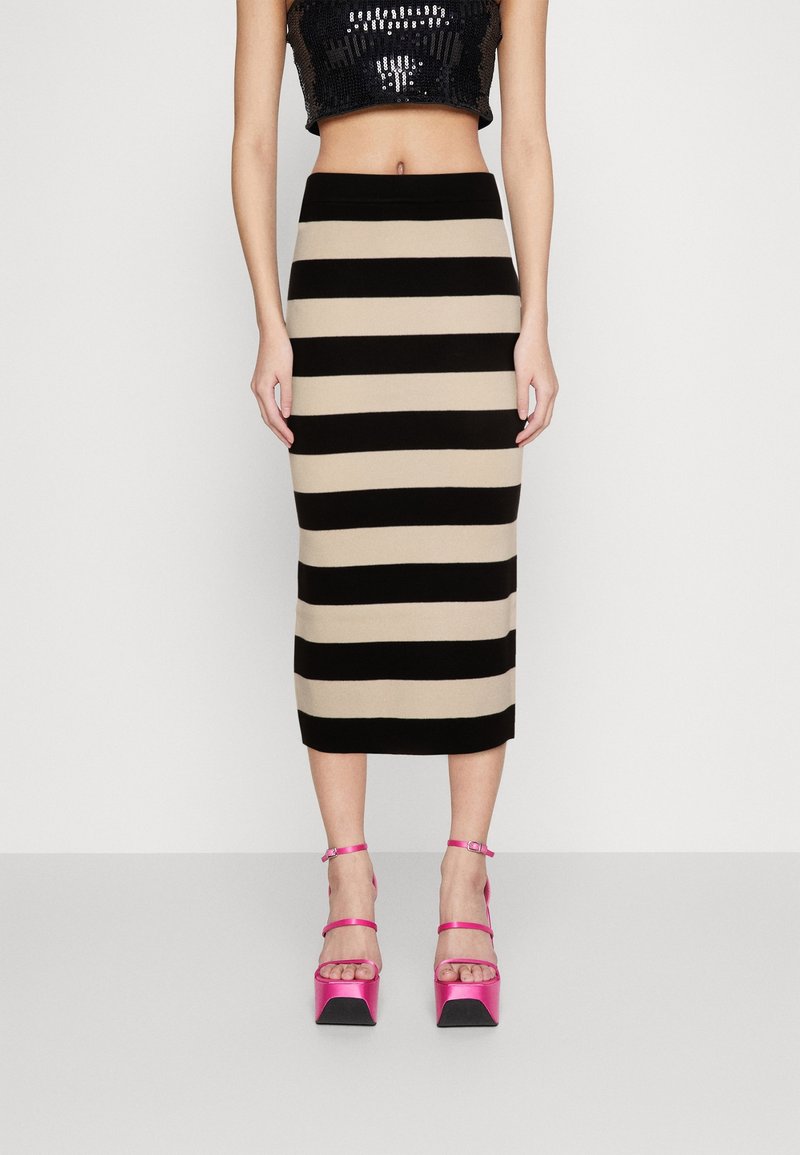 Stickad midikjol med alternerande svarta och beiga ränder. Matchad med rosa högklackade sandaler med ankelremmar.