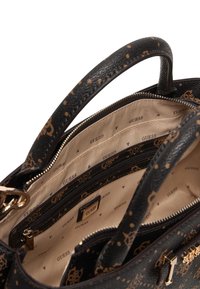 Sac à main noir avec une surface texturée et des accents dorés. Comprend plusieurs compartiments doublés d'un tissu beige avec le logo "GUESS" répété.