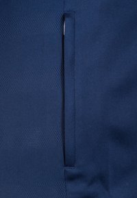 Navy blue fabric with a textured, perforated pattern. Features a vertical seam and a concealed pocket detail for storage.
