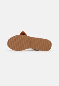 Brown flat sandal sole with horizontal ridges and size 38 marked, viewed from the bottom on a white background.